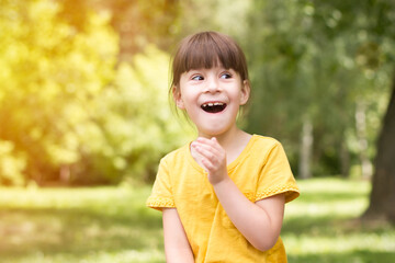 Surprised little girl in a yellow t-shirt on a green background