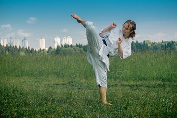 teenage girl training karate kata outdoors, performs the uro mawashi geri (hook kick)