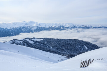 mountains of main Caucasian Ridge covered with snow and forest and wooden fence