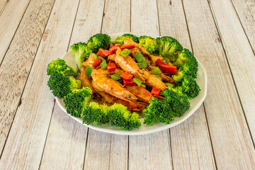 Grilled fried prawns with hot pepper, pieces of green and red peppers and cooked broccoli on white plate