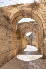 Fototapeta na wymiar Stone arched connections on the quiet small St James Street in the Armenian quarter in the old city of Jerusalem, Israel