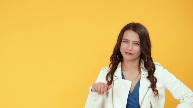 Choice disapproval. Dislike gesture. Bad idea. Dissatisfied joyful smiling brunette girl rejecting offer with thumb down hand nope sign isolated on orange copy space background.