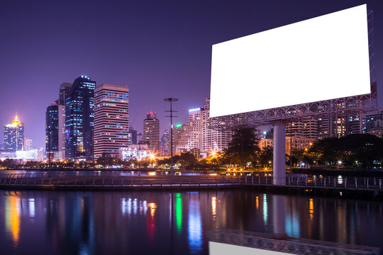 Blank white billboard with urban and lake in the night - can advertisement for display or montage product or business.