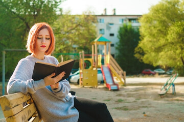 Female student read book in playground, close up. Self-education concept.