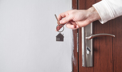 Male hand holding house key at home.