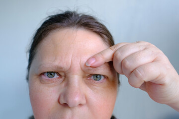 upper part of woman's face, an elderly woman close-up, small and large mimic wrinkles, eyes with...
