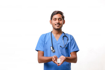 Young indian doctor holding pill in hand.