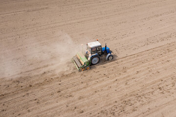 Obraz premium Aerial view of a working tractor. A tractor is plowing a large field. Agricultural machine. 