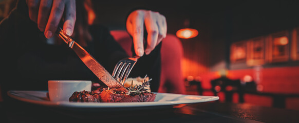 woman hands with fork and knife eating beef steak in cafe