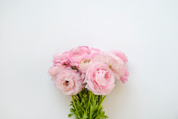 Studio shot of beautiful bouquet of pale pink ranunculus flowers with visible petal texture. Close up composition with bright patterns of flower buds. Top view, isolated, copy space.