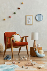 Creative composition of cozy scandinavian child's room interior with mock up poster frame, red armchair, plush toys and hanging decorations. Creative wall, carpet on the parquet floor. Template.