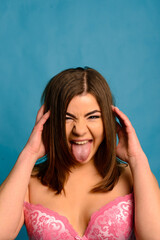 Pretty caucasian woman with plus size body wearing pink lace underwear on blue studio background