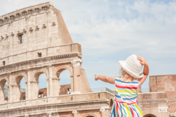 Fototapeta na wymiar little girl points the finger at the coliseum in Rome, Italy. Back view