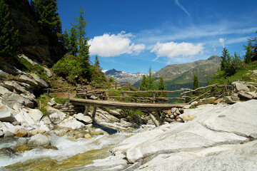 Wooden bridge over a mountain stream in the Italian Alps