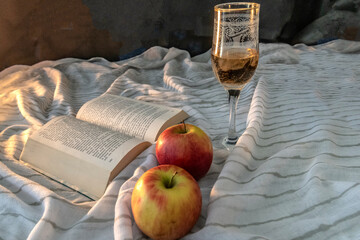 Nature morte avec lumière douce, livre, verre en cristal avec alcool  et deux pommes