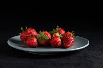 Saucer of fresh red strawberries still with caps