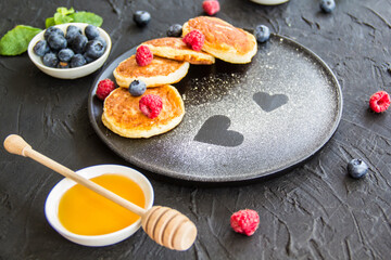 A healthy breakfast of cheese pancakes, berries, and honey. Creative atmospheric decoration