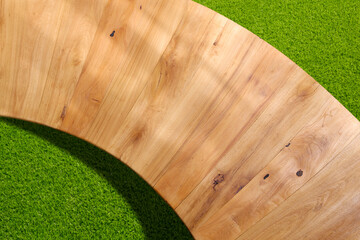 Top view of empty curved wooden table on green lawn background for montage products display and...
