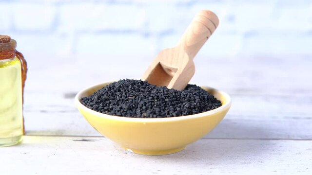 Black Cumin a container with oil in a jar on table.