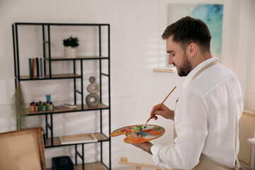 Young man painting with brush in artist studio