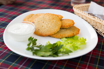 potato pancakes with sour cream and herbs on white plate
