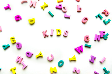 The word "kids" is made up of wooden multicolored letters on a white background. scattered color letters. childrens background