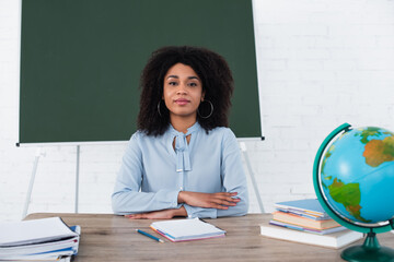 African american teacher sitting at working table in classroom