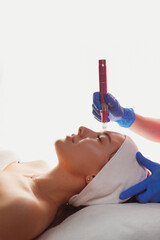 Professional cosmetology. Beautician is using dermapen on woman face skin, side view. Skin beauty and health