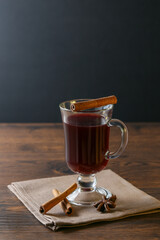 Mulled wine in glass cups with cinnamon and oranges on a wooden table.