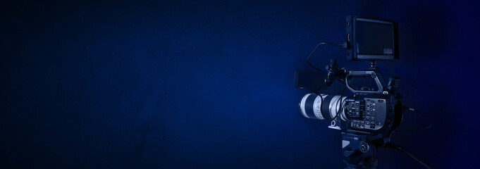 Professional digital video camera on dark blue background with copy space. Television, video...