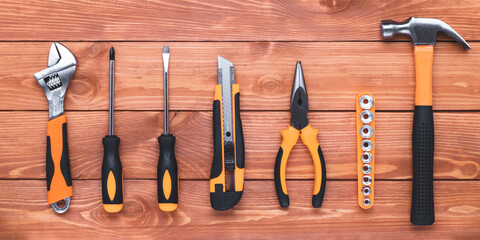 Set of construction tools on a brown wood table. Hammer, wrench, pliers and screwdriver. Postcard for the holiday Labour Day. Equipment, workplace. Flat lay. DIY concept. Overhead view.