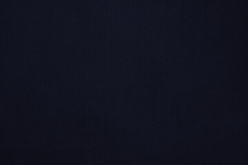 Texture of a dark blue flat fabric of polyester material. Fabric background in dark blue tone.