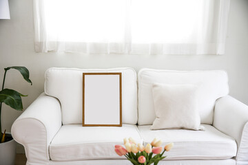 Empty picture frame on a white wall above a sofa.