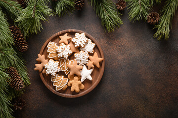 Obraz na płótnie Canvas Christmas homemade assorted glazed cookies in wooden plate on brown background. New Year holiday treats. Top view. Xmas greeting card. Copy space.
