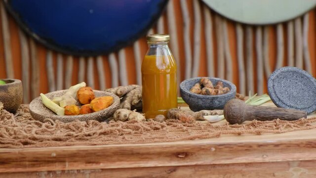 Bottle of Jamu drink- Indonesian herbal beverage with natural ingredients: turmeric, ginger, lime, palm sugar, lemongrass, tamarind on wooden table. Healthy lifestyle