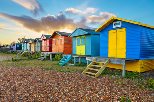Colourful beach huts on shingle beach at sunrise, Whitstable, Kent, England