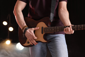 Obraz na płótnie Canvas Man playing electric guitar on stage, closeup. Rock concert