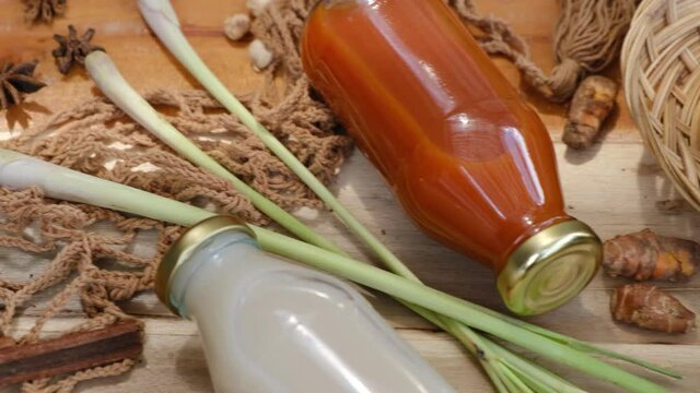 Many different Jamu drinks- Indonesian herbal beverage in glass bottles with natural ingredients: turmeric, ginger, lime, palm sugar, lemongrass, tamarind on wooden table. Healthy lifestyle. Flat lay
