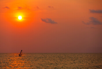 Surfer surfing alone in sea at sunset