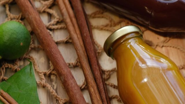 Many different Jamu drinks- Indonesian herbal beverage in glass bottles with natural ingredients: turmeric, ginger, lime, palm sugar, lemongrass, tamarind on wooden table. Healthy lifestyle. Flat lay