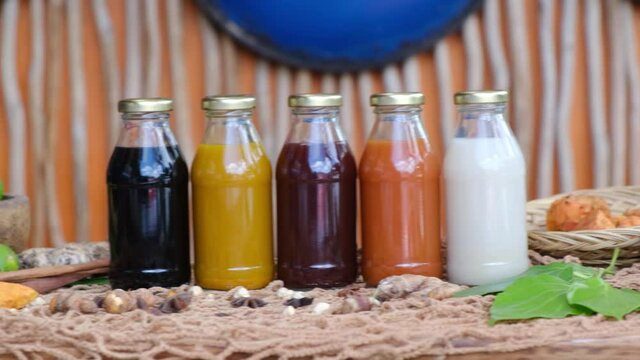 Many different Jamu drinks- Indonesian herbal beverage in glass bottles with natural ingredients: turmeric, ginger, lime, palm sugar, lemongrass, tamarind on wooden table. Healthy lifestyle