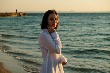 Fototapeta na wymiar Pretty girl near the sea. Young woman enjoying morning dawn at the sea.