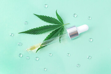 Serum hemp cosmetics product dropper or pipette with cannabis oil next to fresh hemp leaf