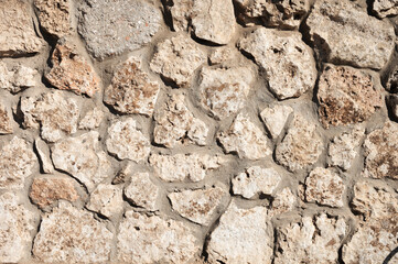 The stone wall is lined with natural stone and cemented. Natural building material. Medieval background