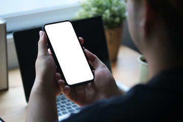 Behind shoulder view with male using smartphone in front of the laptop, Blank screen of smartphone.