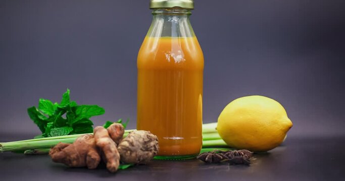 Stopmotion of many different Jamu drinks- Indonesian herbal beverage in glass bottles with natural ingredients: turmeric, ginger, lime, palm sugar, lemongrass, tamarind on wooden table. Healthy eating