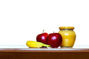 Honey jar, red apples and banana on the table on a white background. honey and fruits. Still life on a white background. 