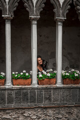 beautiful Mediterranean woman posing with her puppy among the columns of the entrance cloister of Villa Rufolo in Ravello on the Amalfi coast