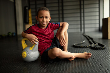 Smiling boy chill with dumbbell on mat. Purposeful kid set goal to become champion in sport. Follow...