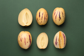 Whole and cut pepino melons on green background, flat lay